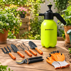 A bright lime green hand-pumped watering can with a black sprayer and the brand name 'paankhuri' printed on the front, displayed on a wooden table alongside a gardening tool set with orange handles and a pair of orange-and-white gloves. The background is a lush, blurred garden with potted plants.
